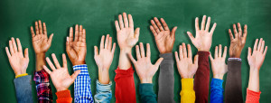 Students raised hands with chalkboard background