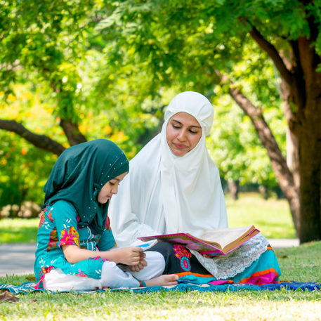 mother and her daughter reading a book in a park