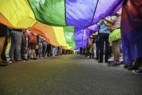 Legs of many people holding a rainbow banner flag