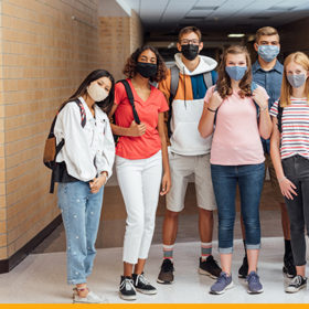 group of diverse highschool students with masks on standing in a hallway
