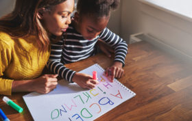 Learning the alphabet at home with her mom, black mother and child